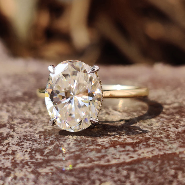 Hidden halo oval engagement ring in white and yellow gold band.