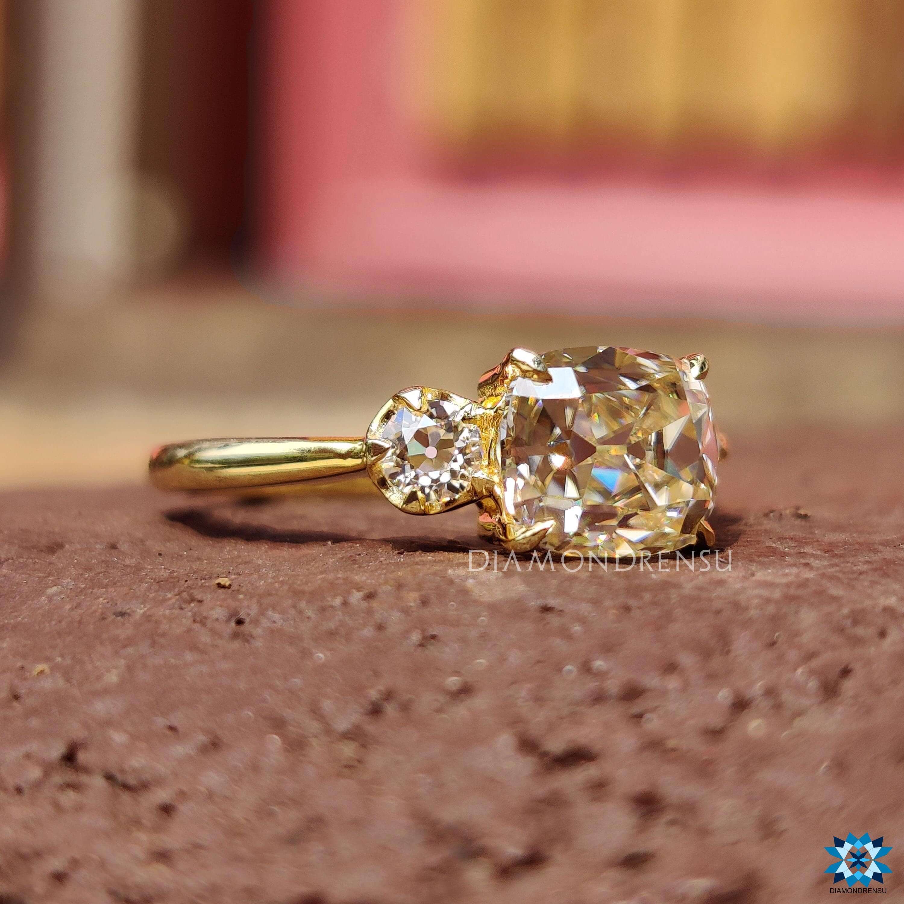 Light yellow moissanite ring with a cushion old mine cut center and matching side stones.