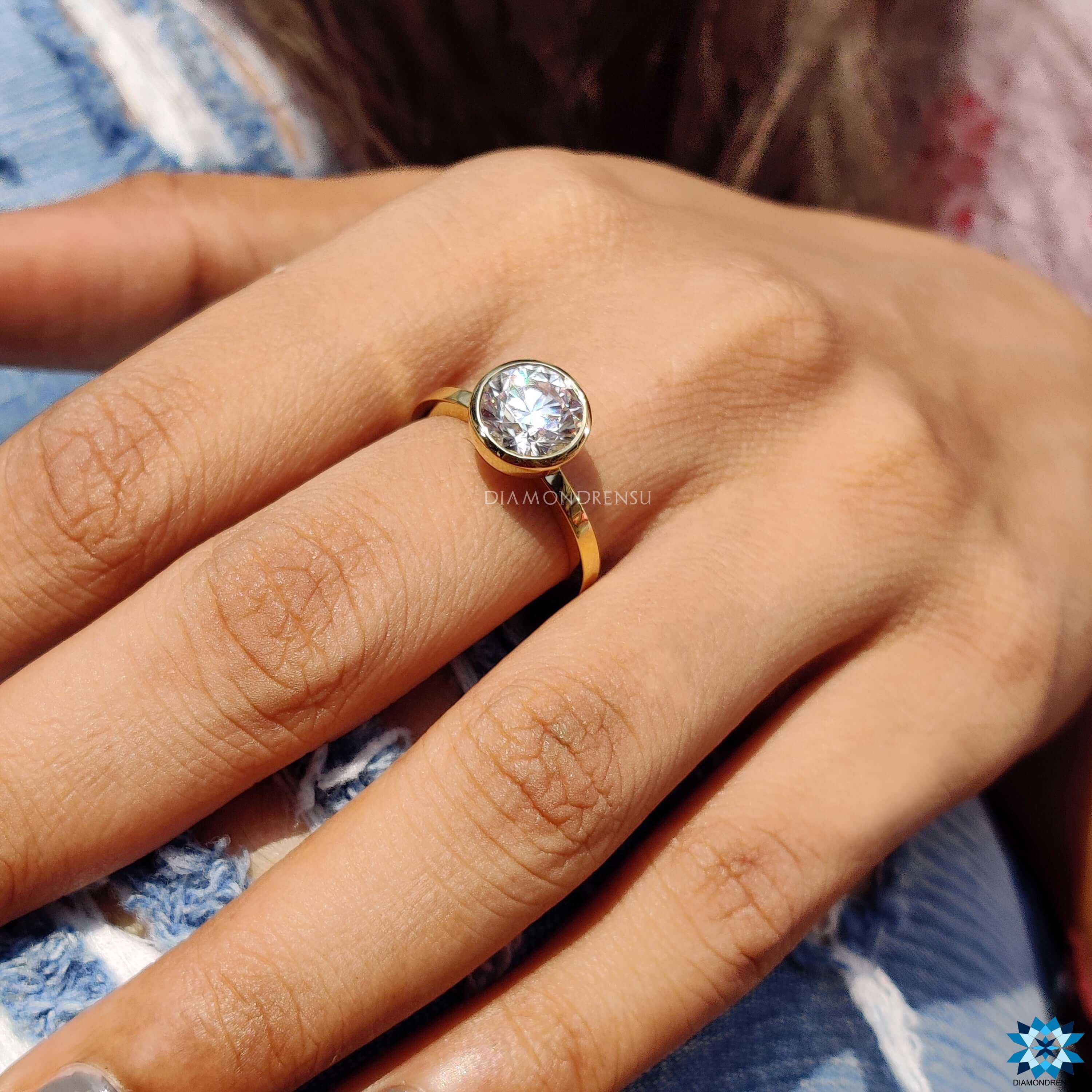 Buy Moissanite ring with yellow gold bezel setting and round cut brilliance.