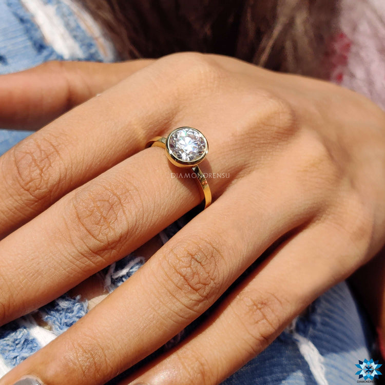 Buy Moissanite ring with yellow gold bezel setting and round cut brilliance.