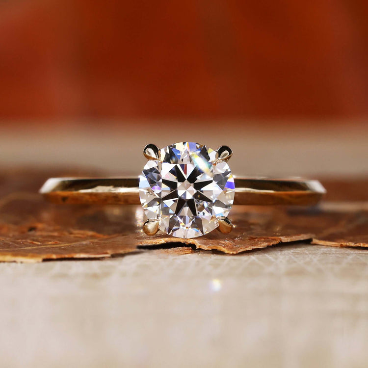 Round solitaire engagement ring with a round brilliant cut diamond in a 4 prong claw setting for timeless elegance.