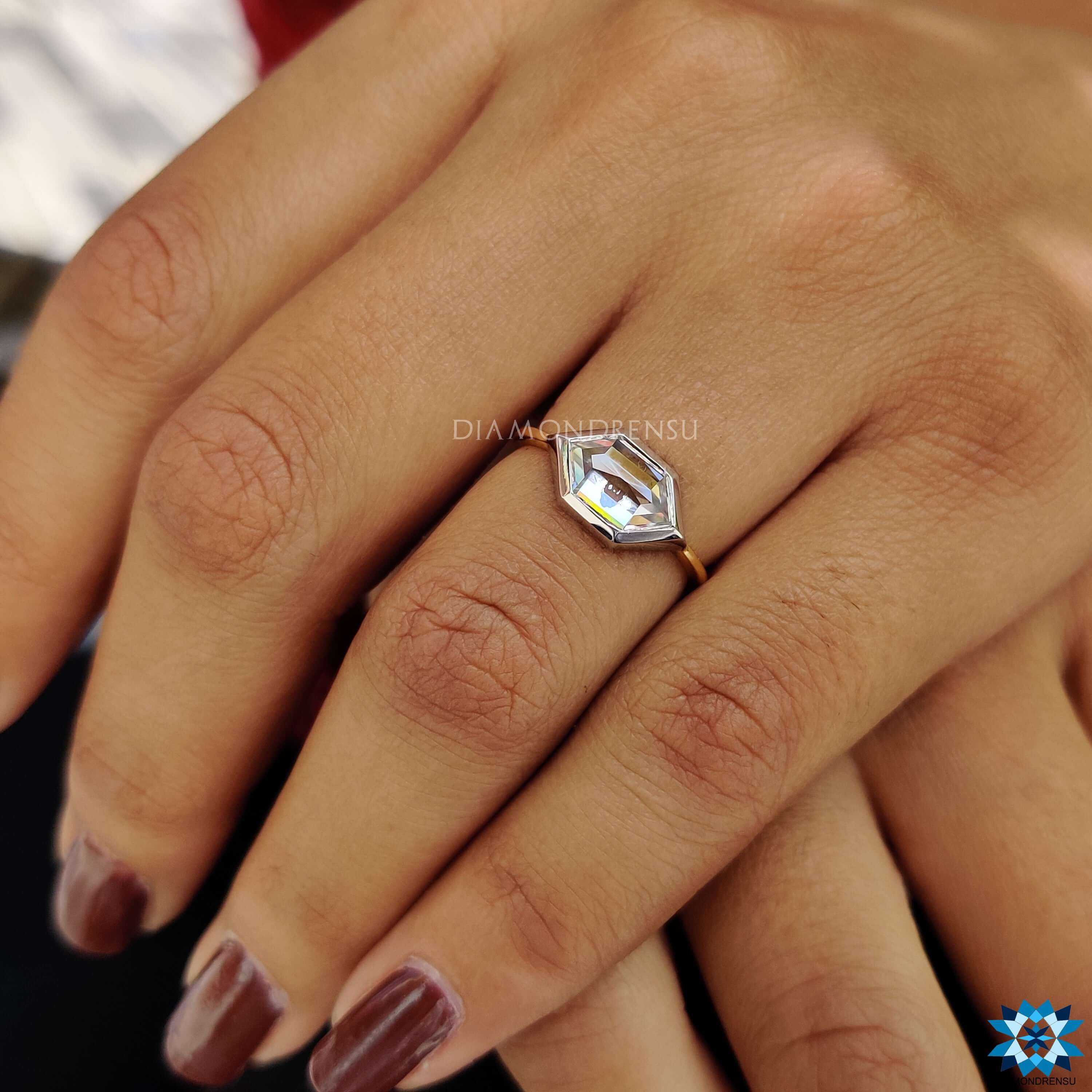 Two-tone white and yellow gold engagement ring with bezel set moissanite.