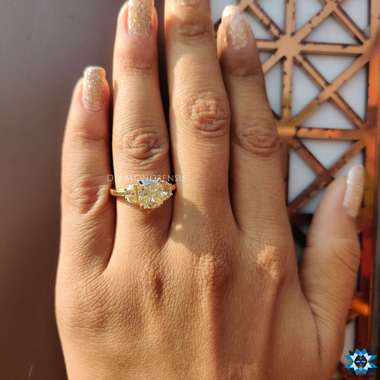 Prong setting three stone moissanite ring in yellow gold.