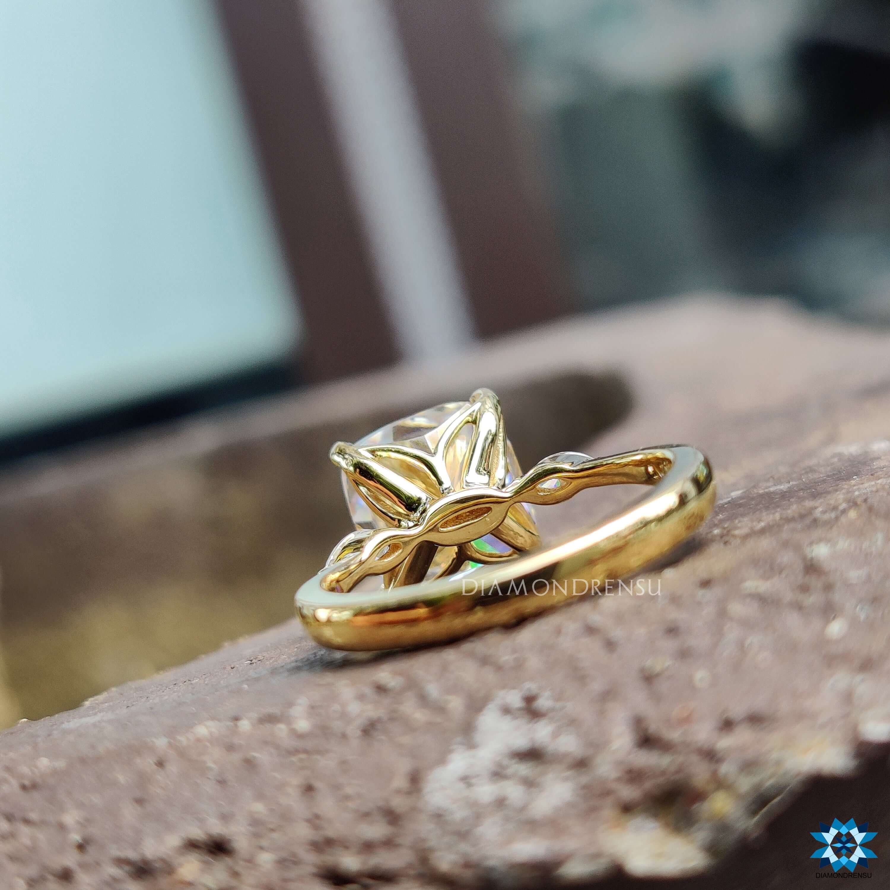 4 prong claw setting holding a cushion cut moissanite with two side stones.