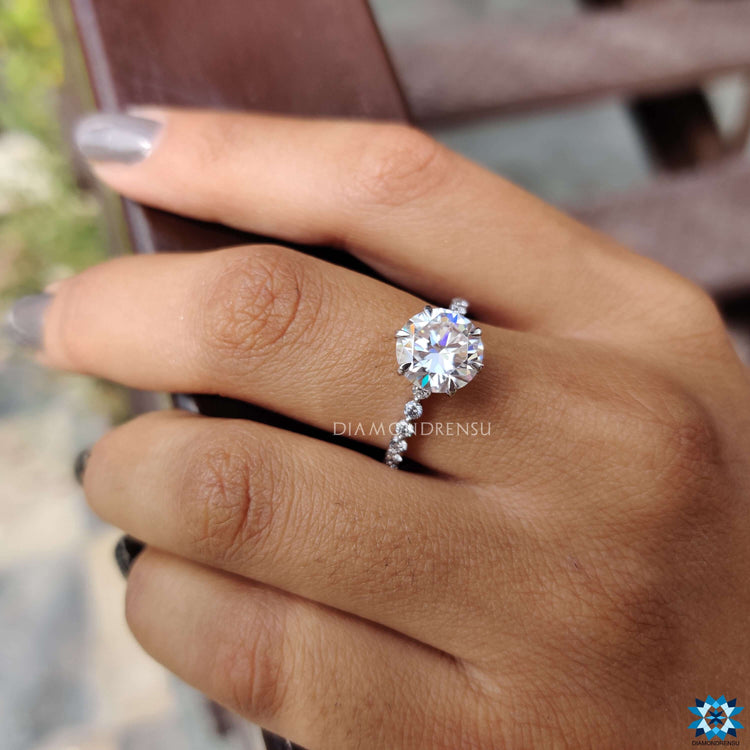 Round cut moissanite ring in white gold with a pave setting.