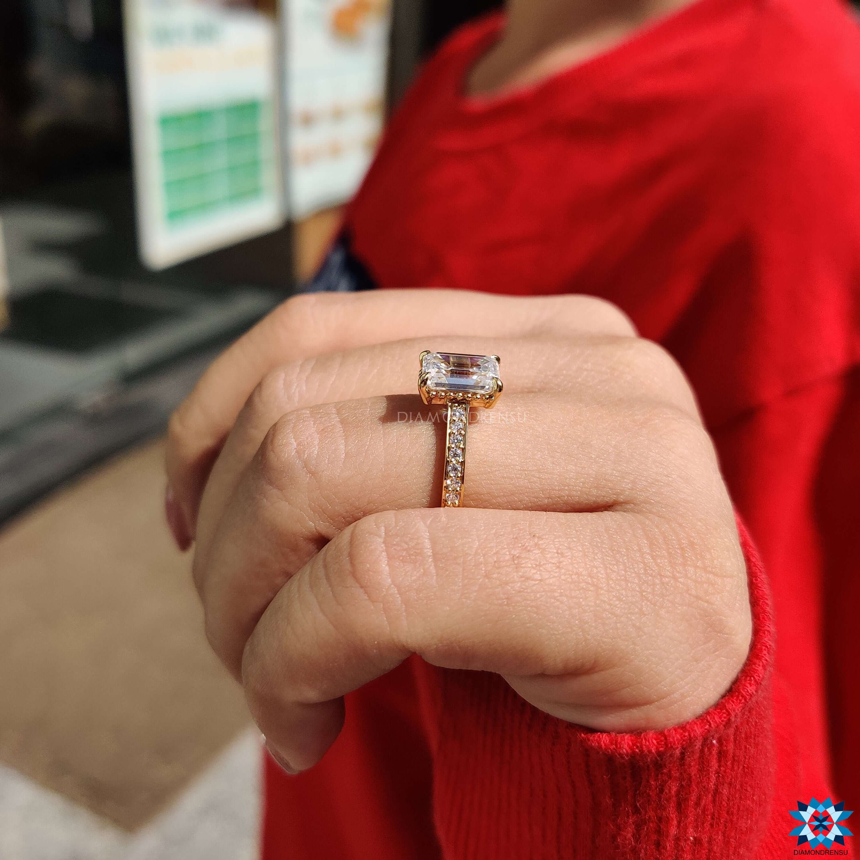 Yellow gold engagement ring with pave band and emerald moissanite center.