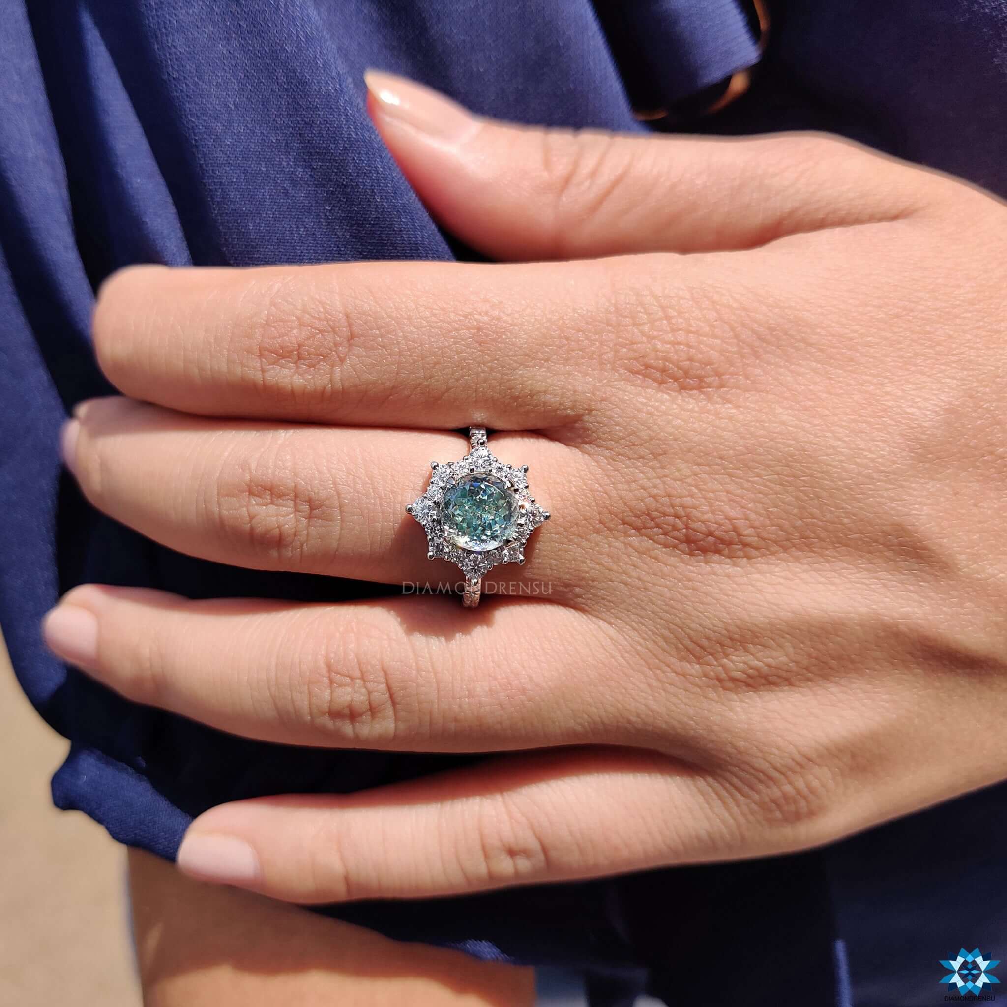 Round cut cyan blue moissanite with halo design.