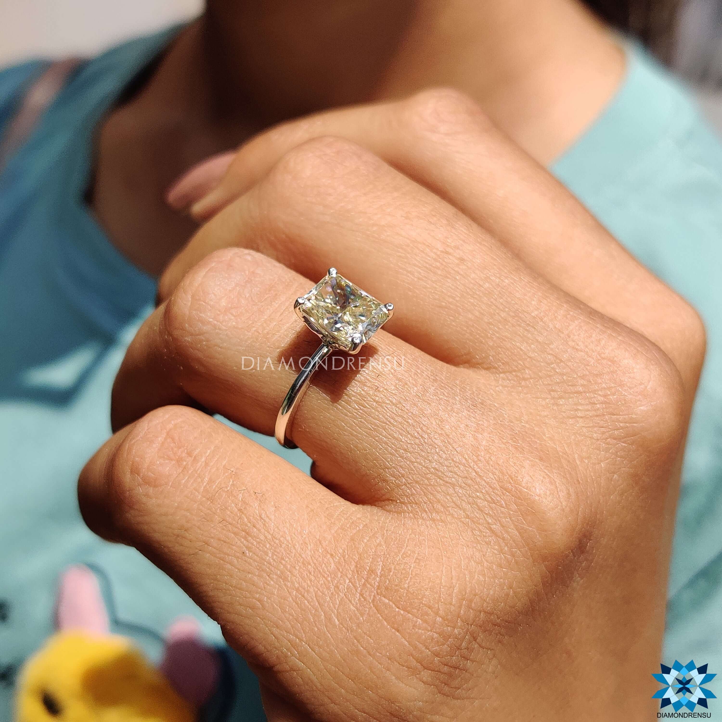 White gold engagement ring with 4 prong setting and radiant cut moissanite centre.