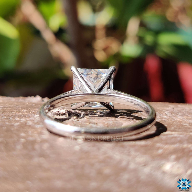 Princess solitaire ring with a 4 tab prong setting that holds the stone in place.