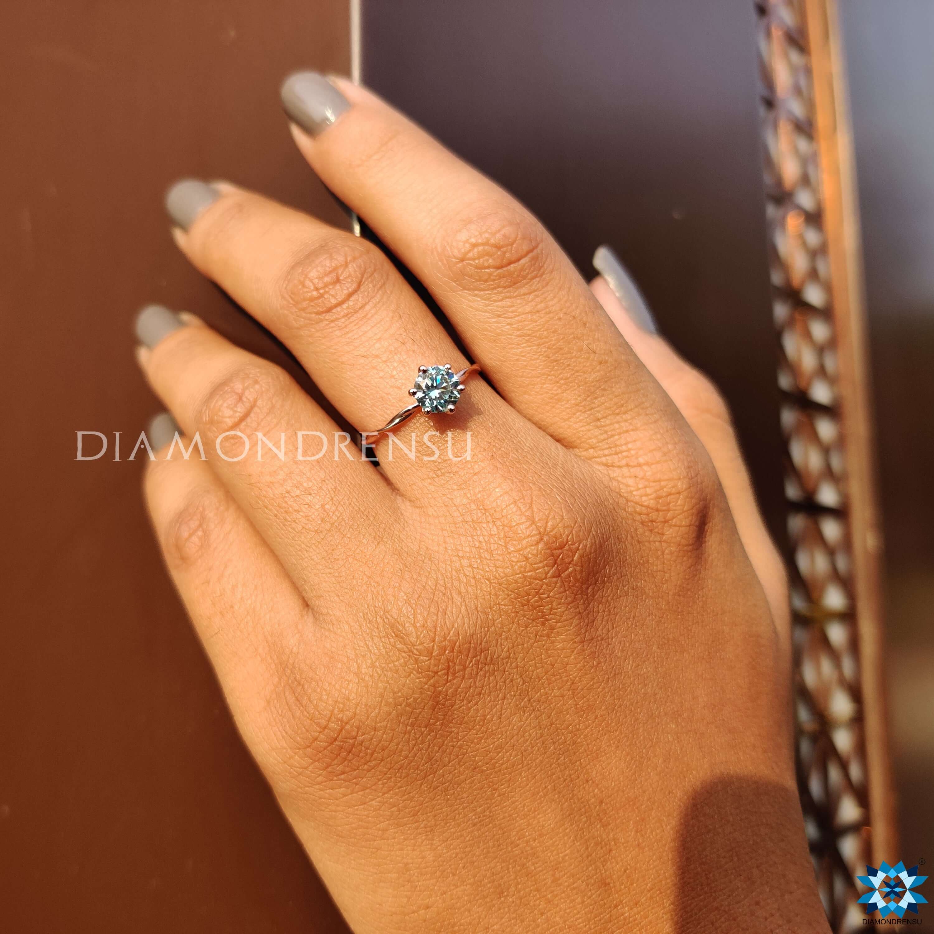 Rose gold engagement ring with a cyan blue moissanite.