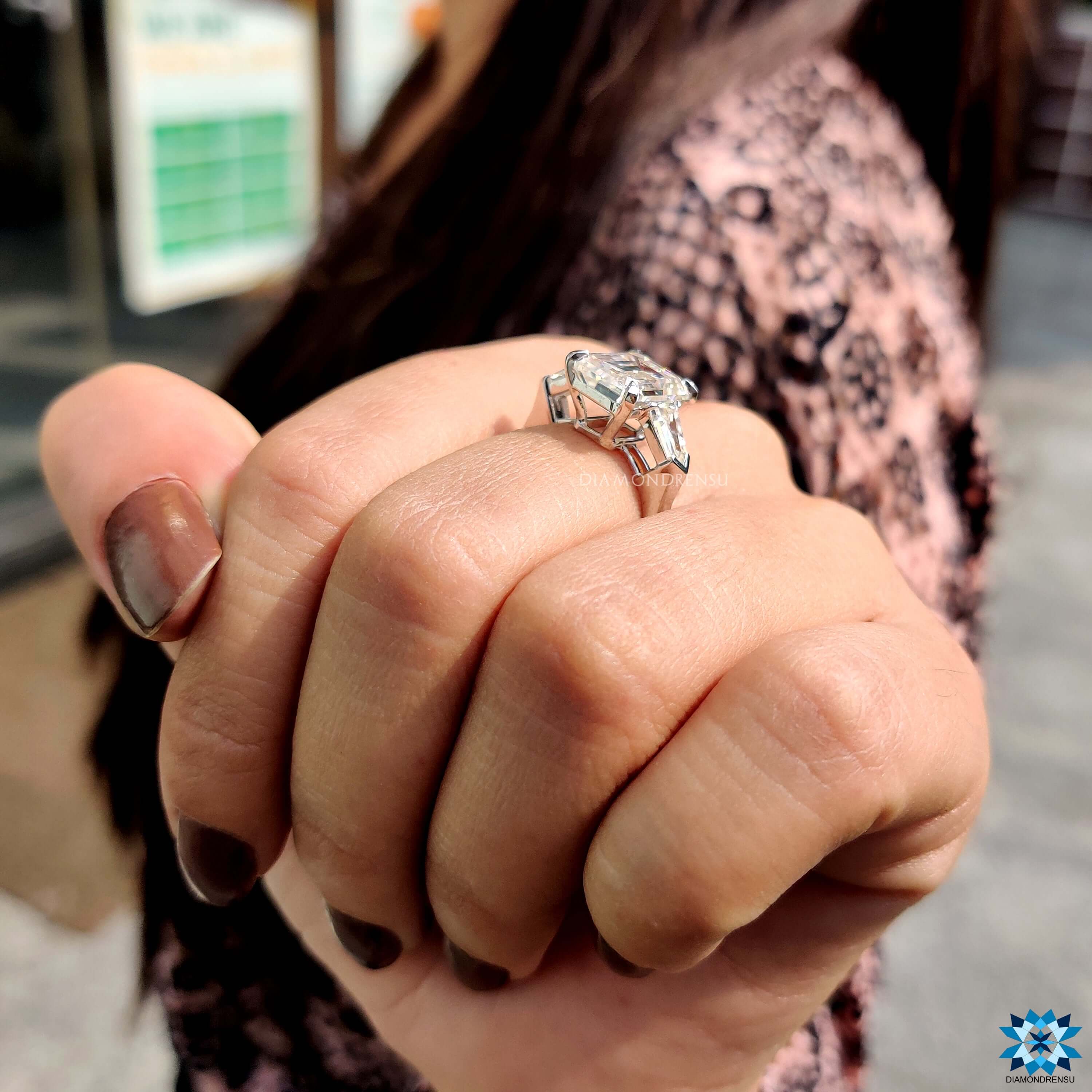 Elegant three stone moissanite ring in white gold with emerald center.