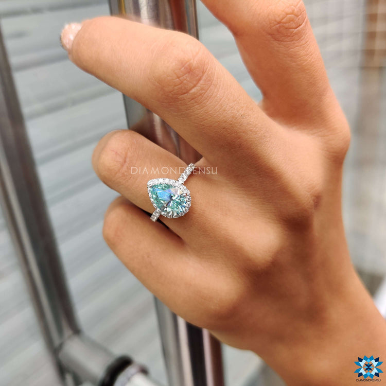 Prong setting ring designed with pear shaped moissanite and side pave stones.