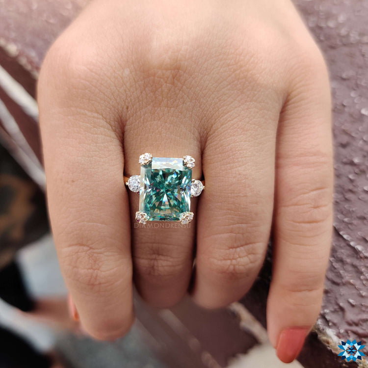 Cyan moissanite engagement ring with round side stones.