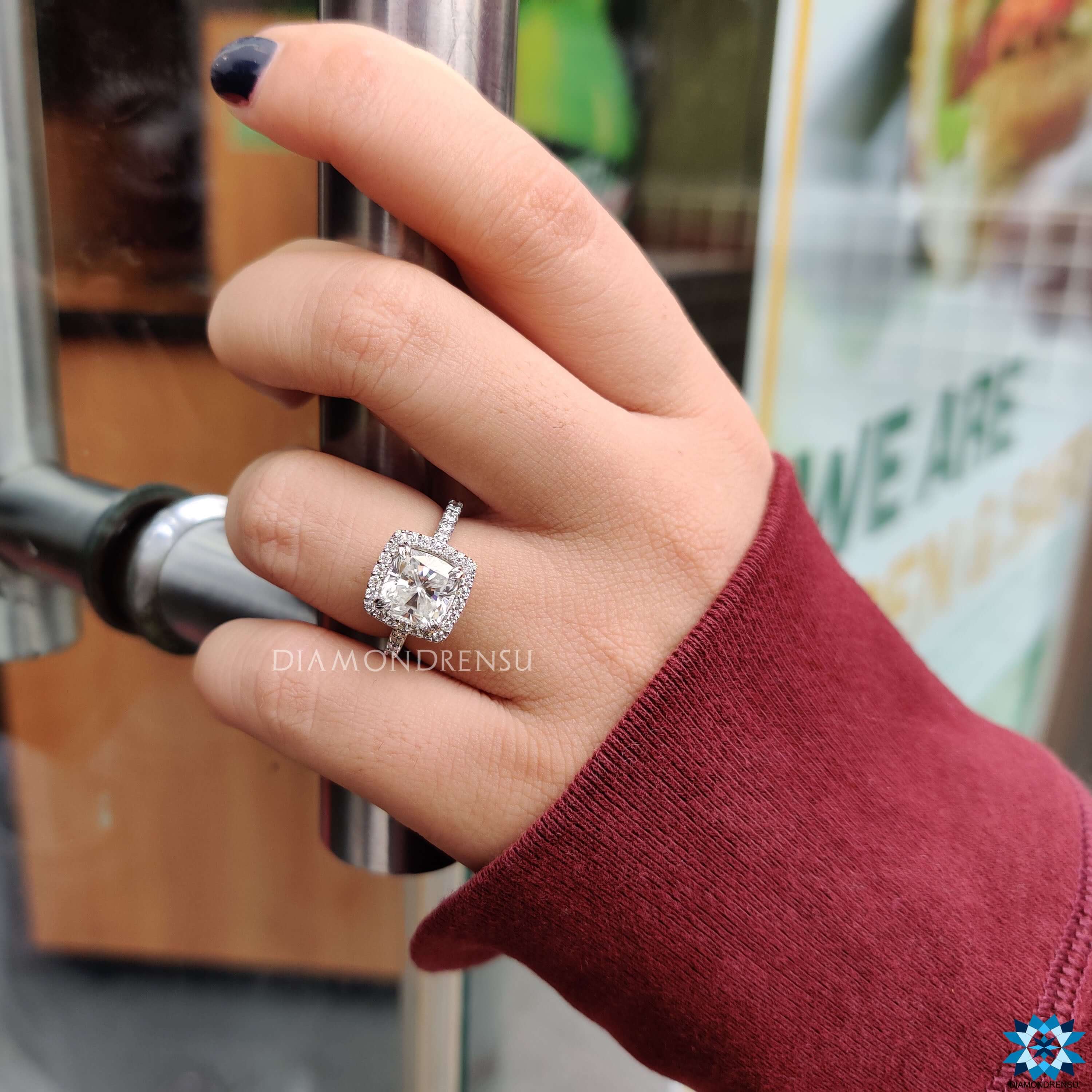 White gold moissanite ring with halo and round pavé accents.
