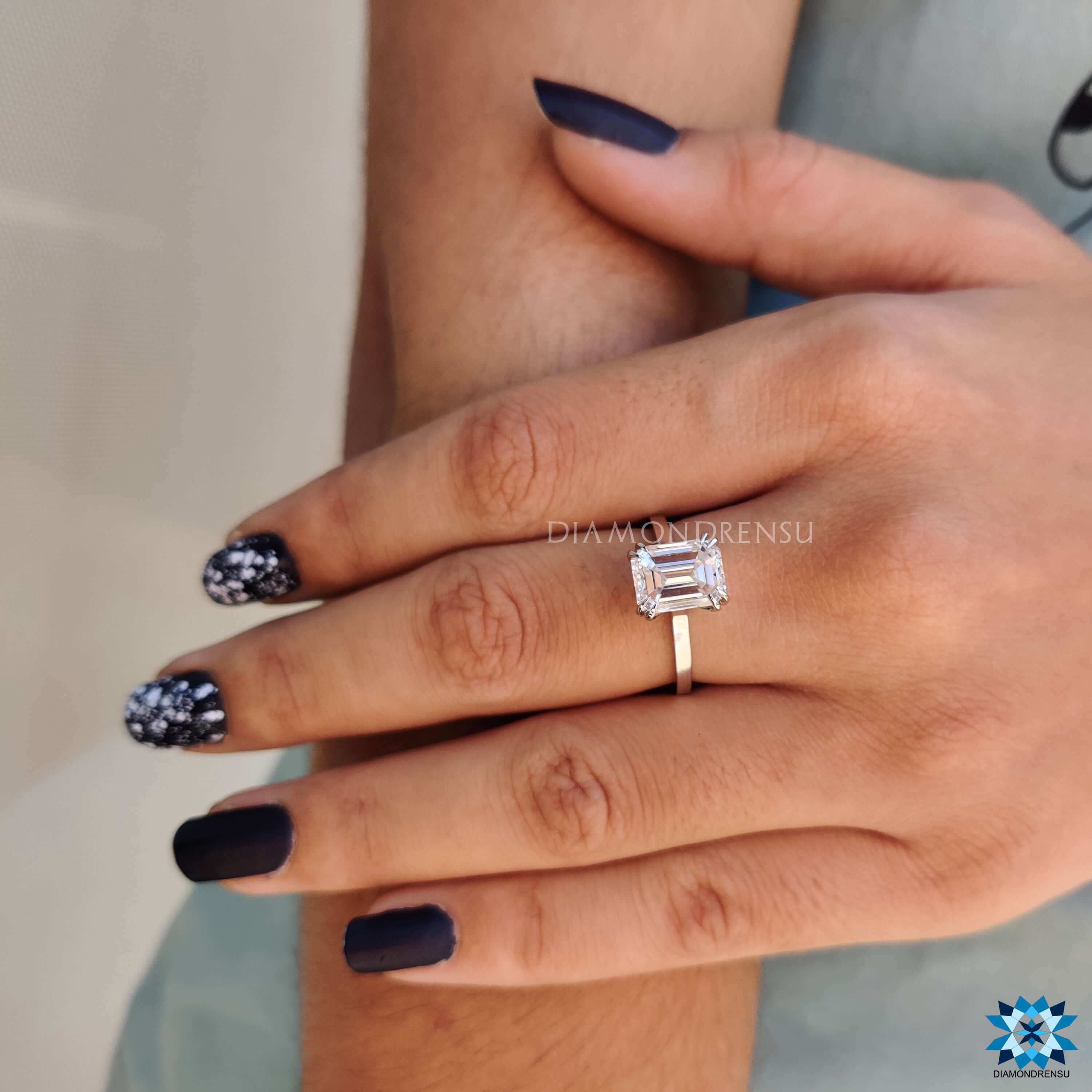 Custom engagement ring with white gold and emerald cut center.