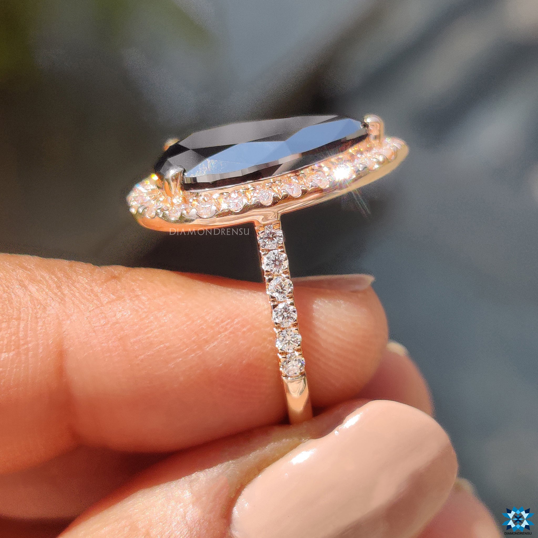 Rose gold ring showcasing black moissanite with 3 round prong halo setting.
