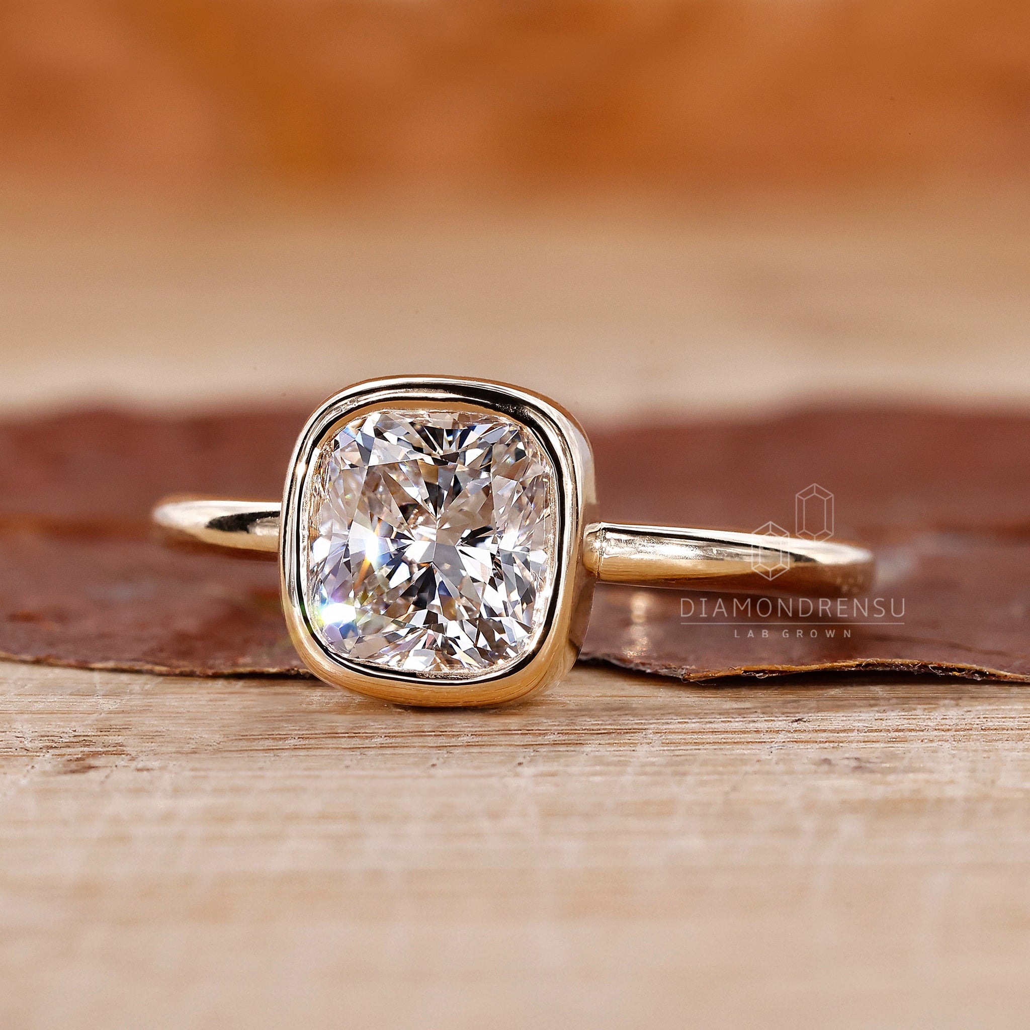 Yellow gold ring holds the diamond in a bezel set engagement ring style.
