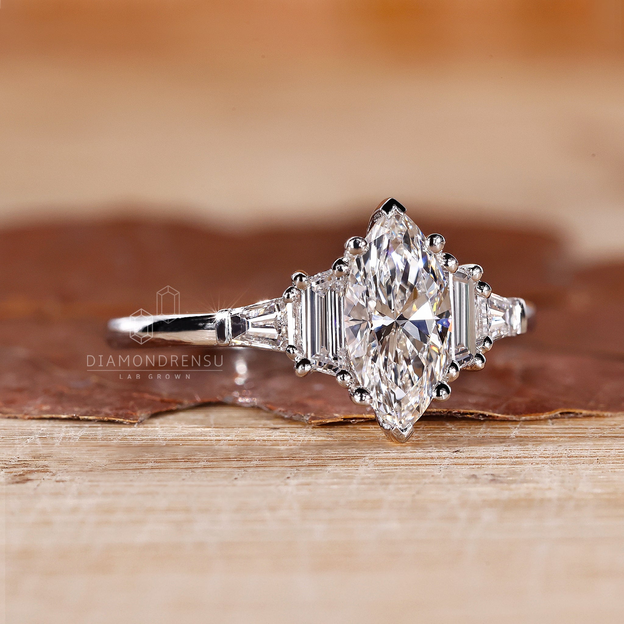 UK engagement ring features five diamonds with marquise and trapezoid shapes.

