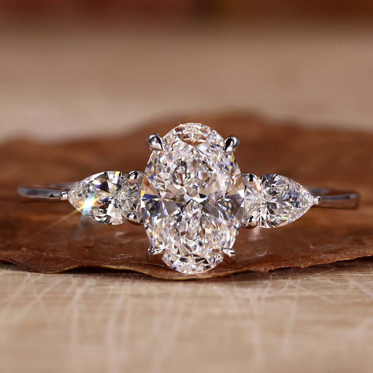 Three stone ring featuring an oval diamond with pear side stones, perfect for a unique engagement ring design.