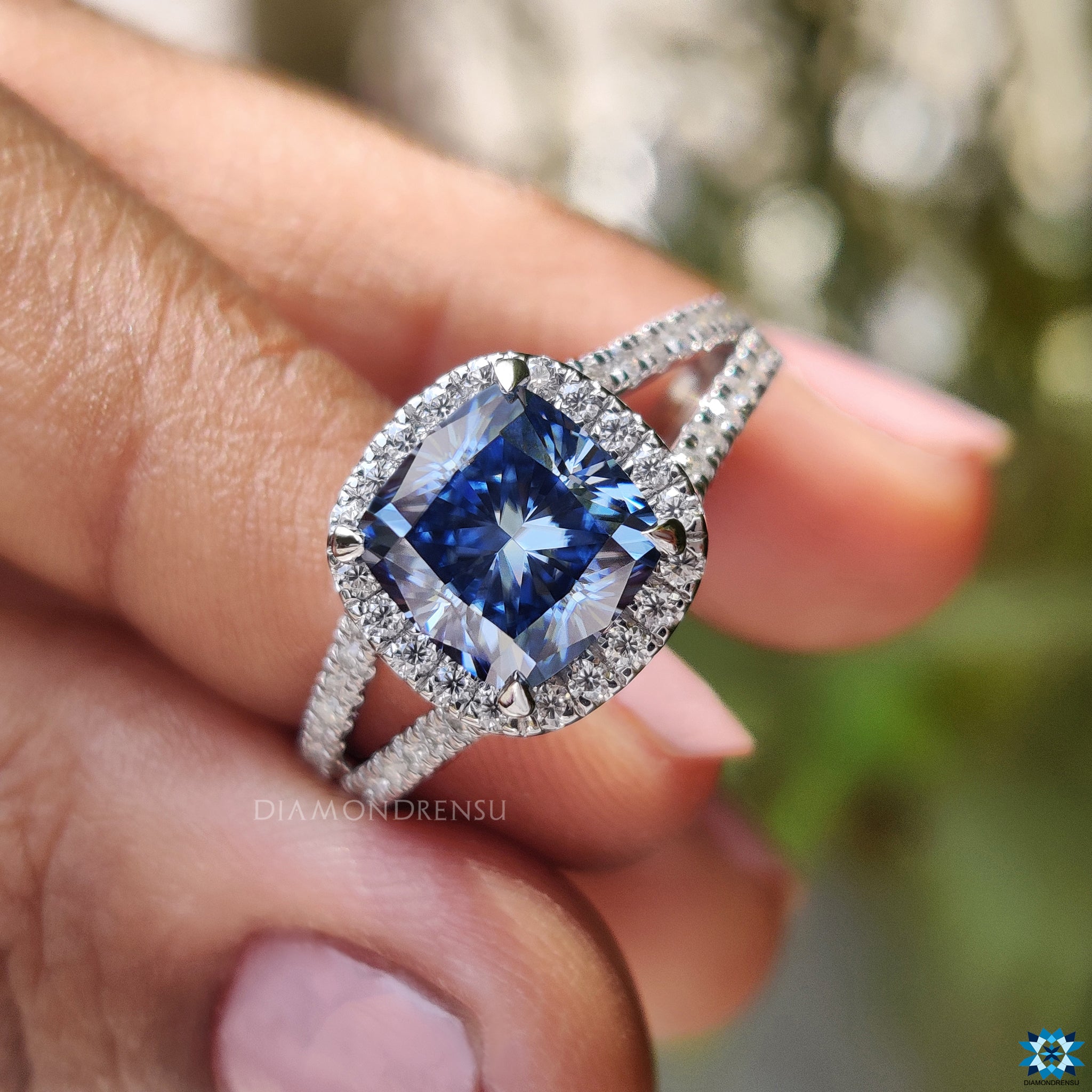 Diamondrensu UK engagement ring featuring cushion cut dark blue moissanite center stone.
