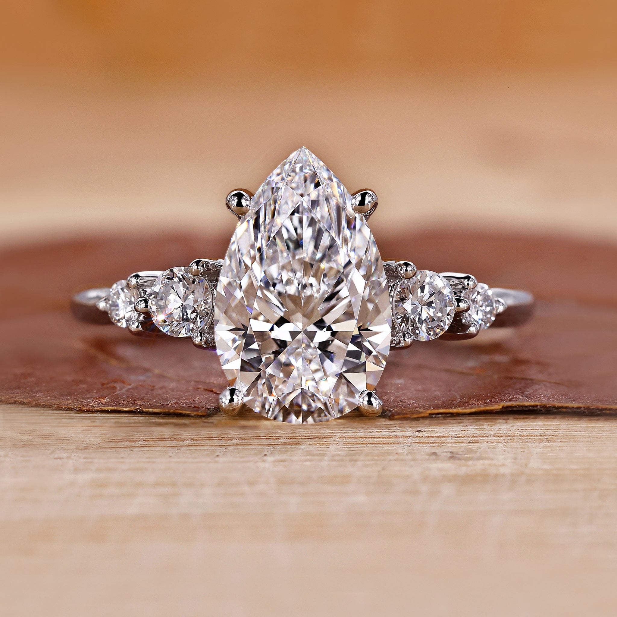 Pear cut diamond engagement ring with five round side stones.
