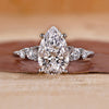 Pear cut diamond engagement ring with five round side stones.
