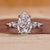 Pear cut diamond engagement ring with five round side stones.
