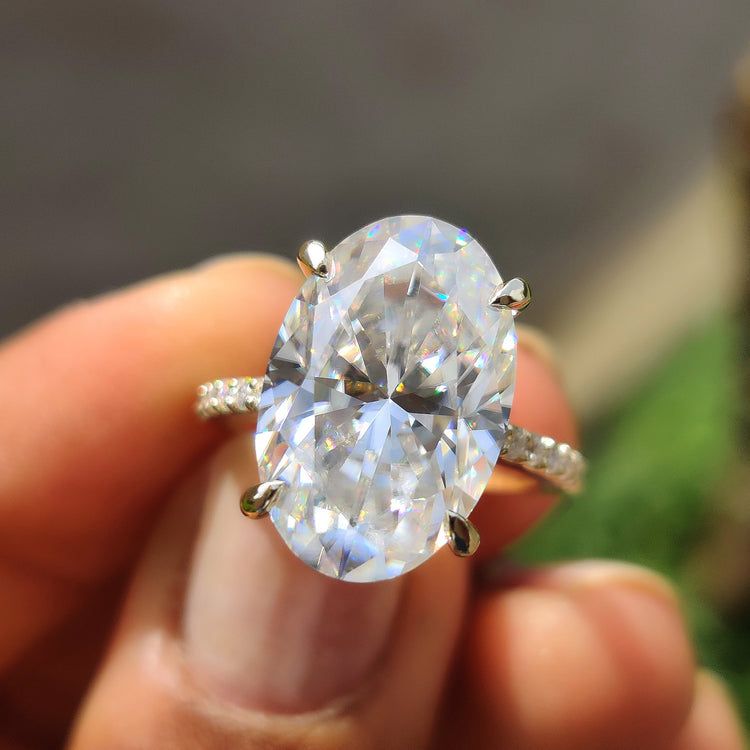 7.70 carat oval cut moissanite ring with hidden halo and yellow gold pave band.
