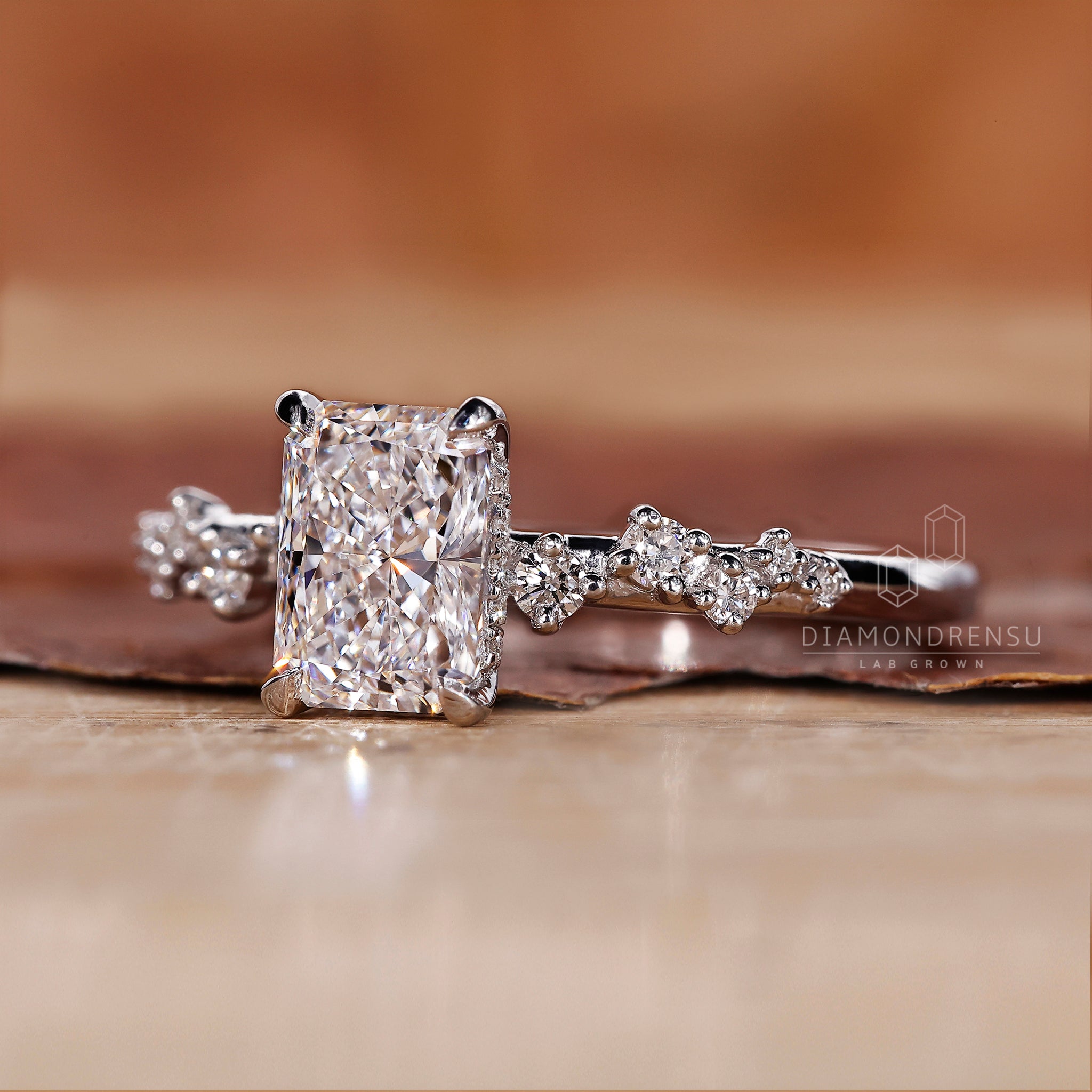 White gold ring with radiant cut diamond and pave detail.
