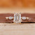 5 stone engagement ring with emerald center diamond and yellow gold setting.
