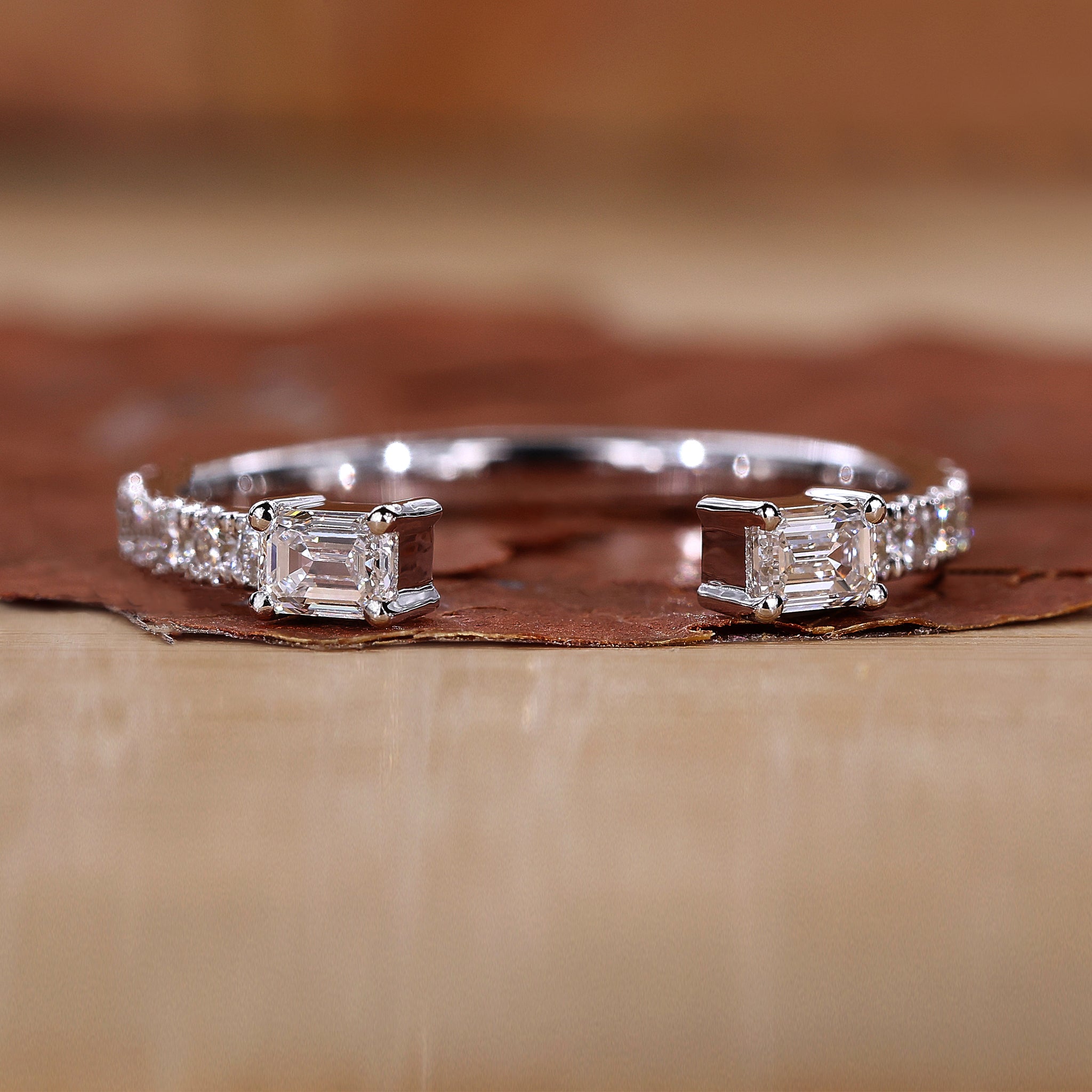 Open wedding band with emerald and round cut diamonds

