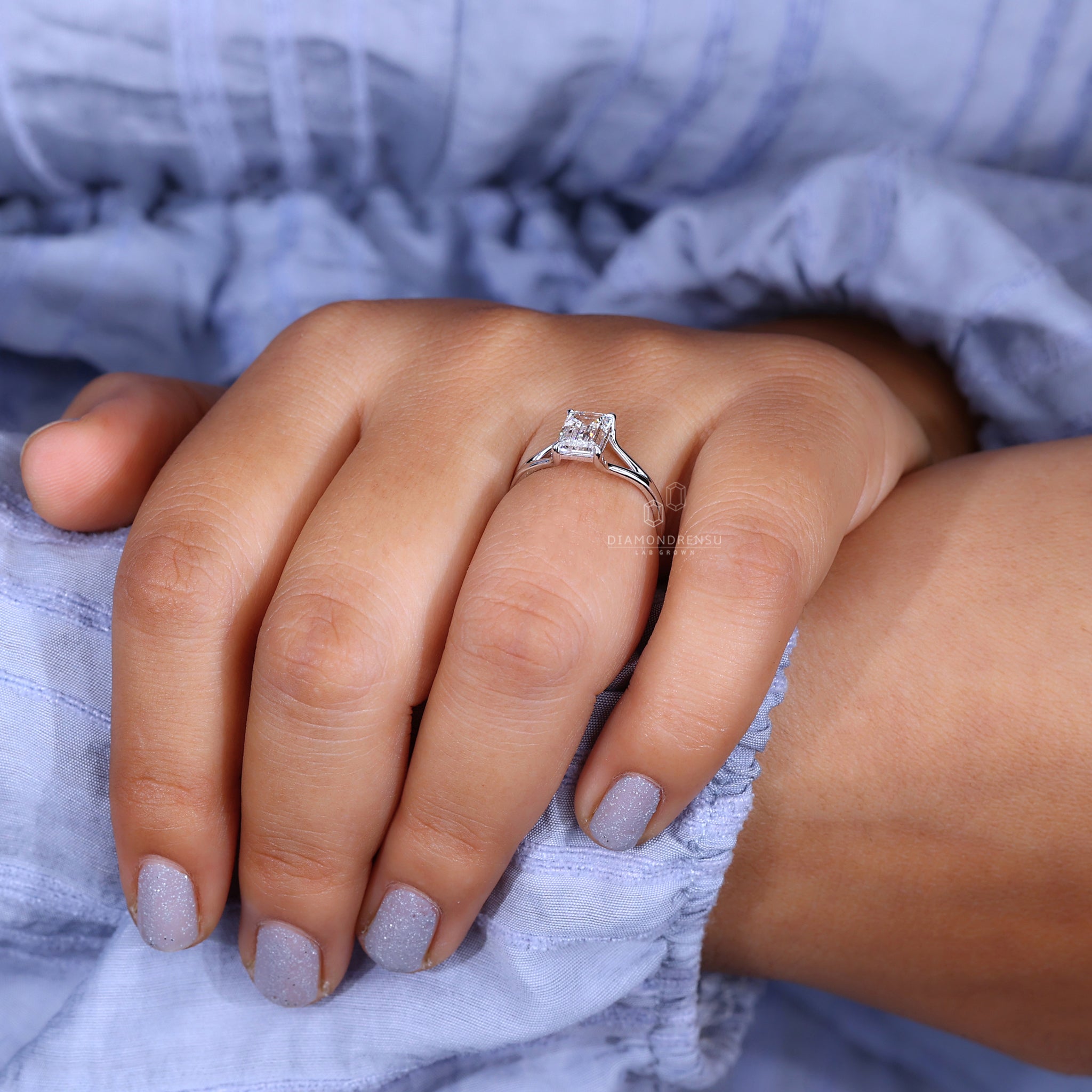 Claw prongs securely hold the emerald cut diamond.