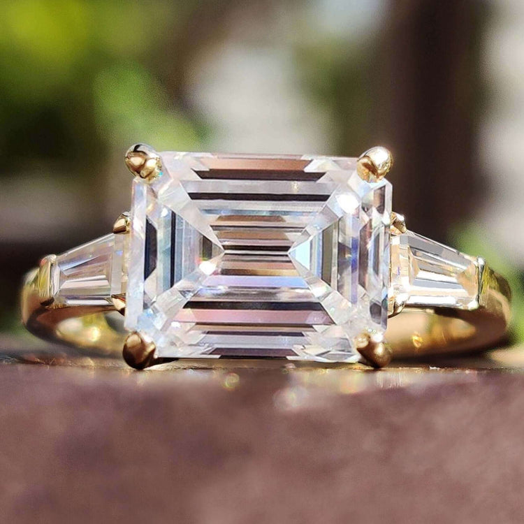 Emerald cut moissanite ring with baguette side stones.
