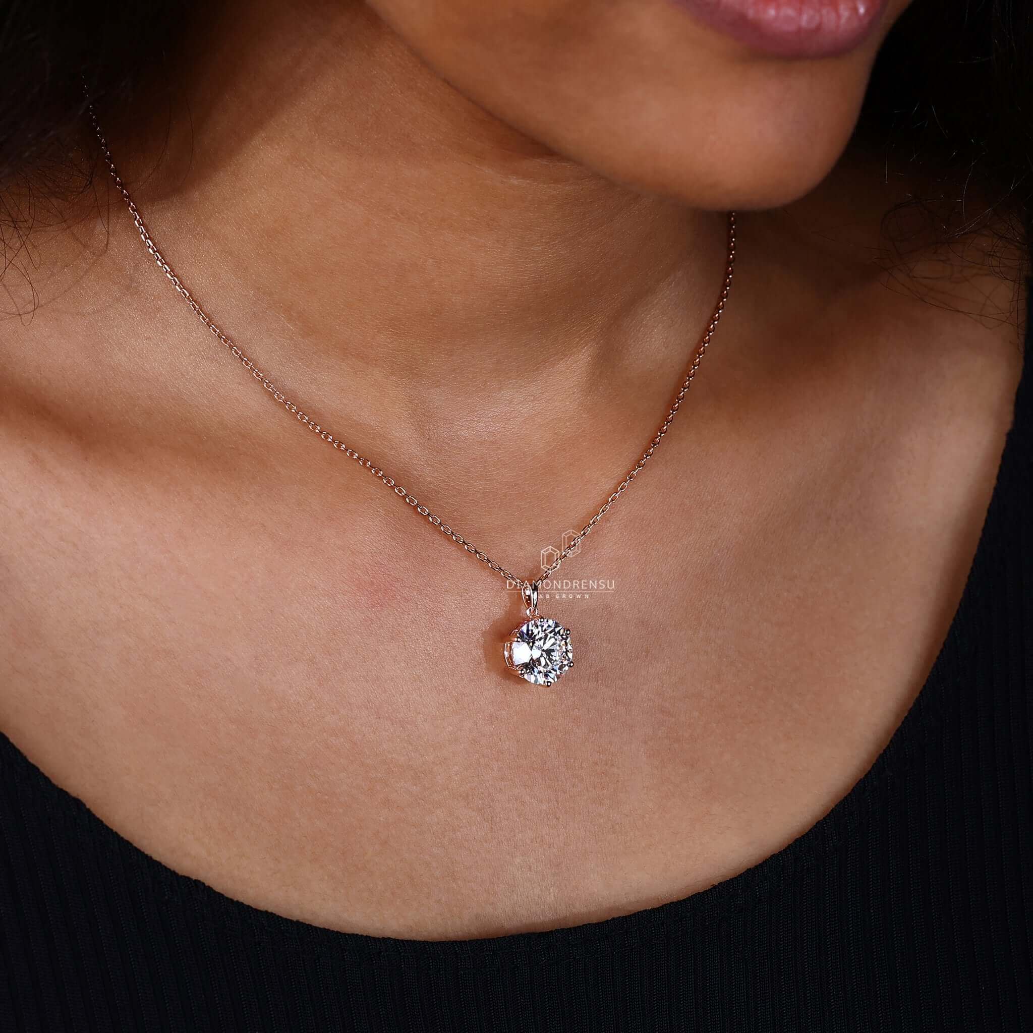 Elegant round gold pendant with a sparkling diamond on a model.