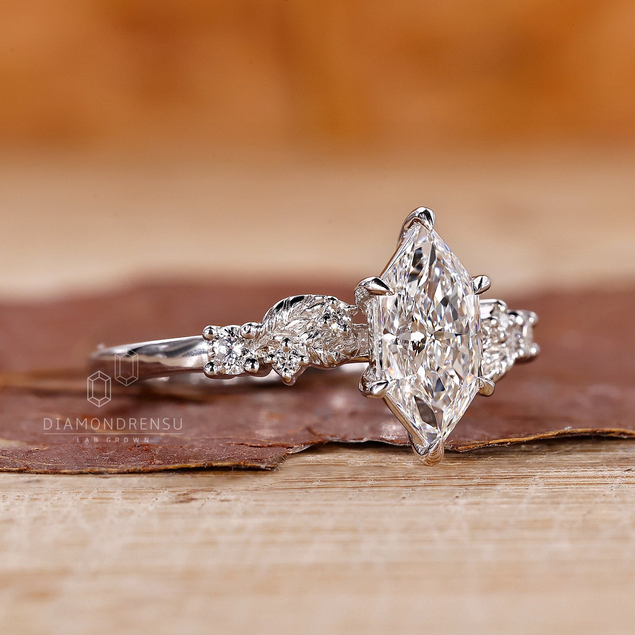 White gold engagement ring with round side stones and claw prong setting.
