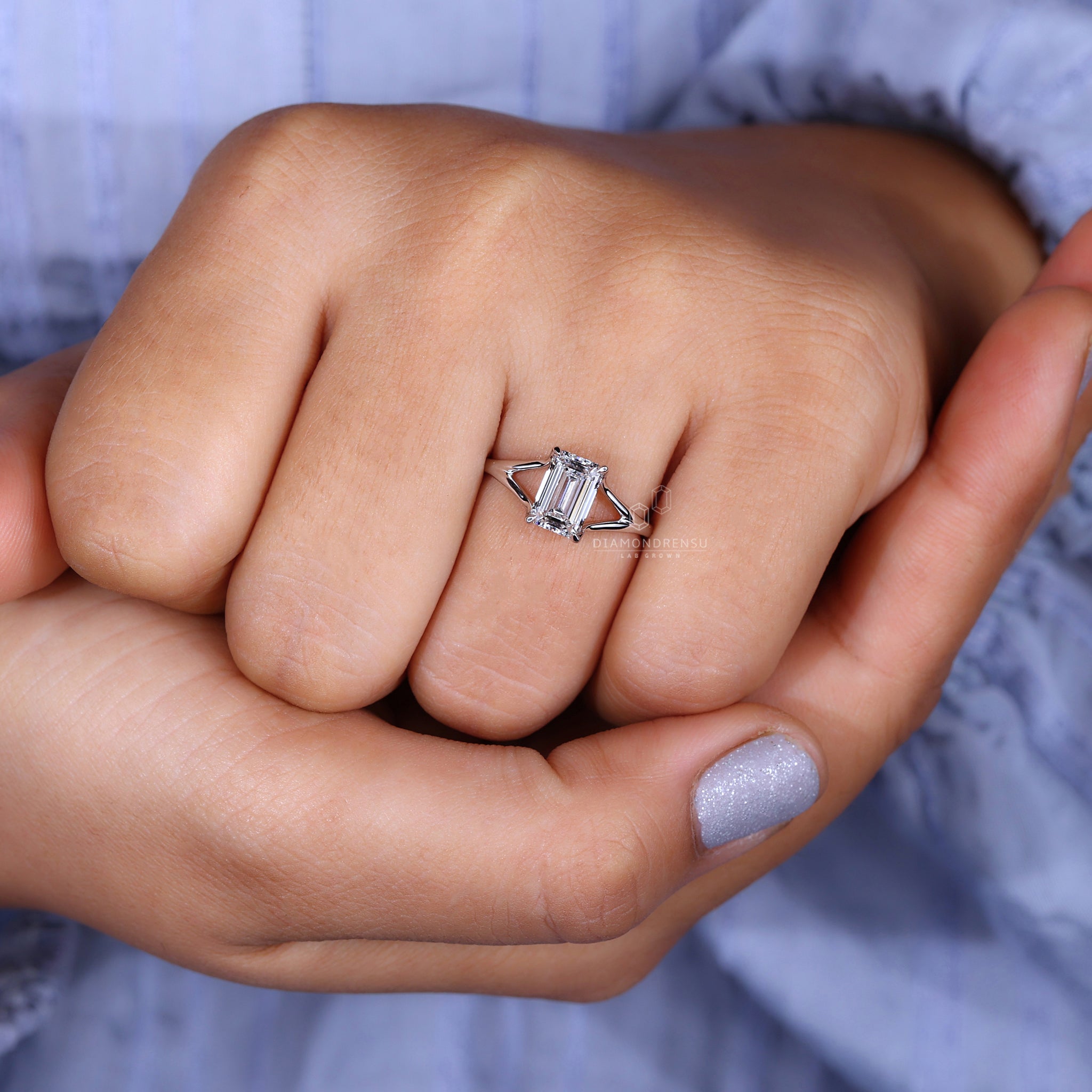 Model wearing a solitaire emerald cut ring, showcasing its brilliance.