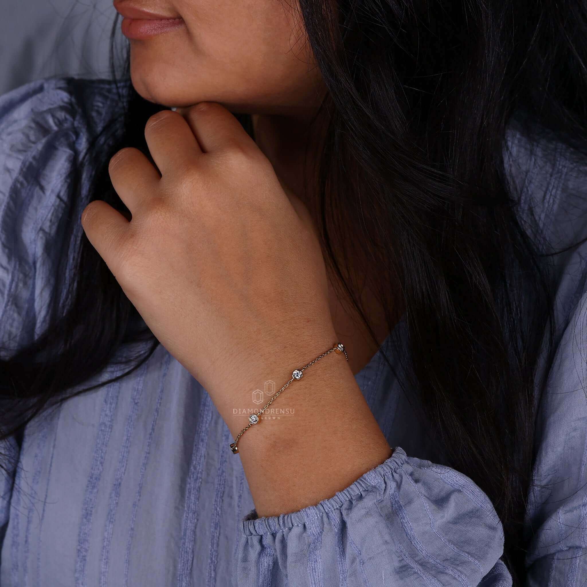 Gold chain bracelet paired with a bezel set diamond bracelet on a model's wrist.