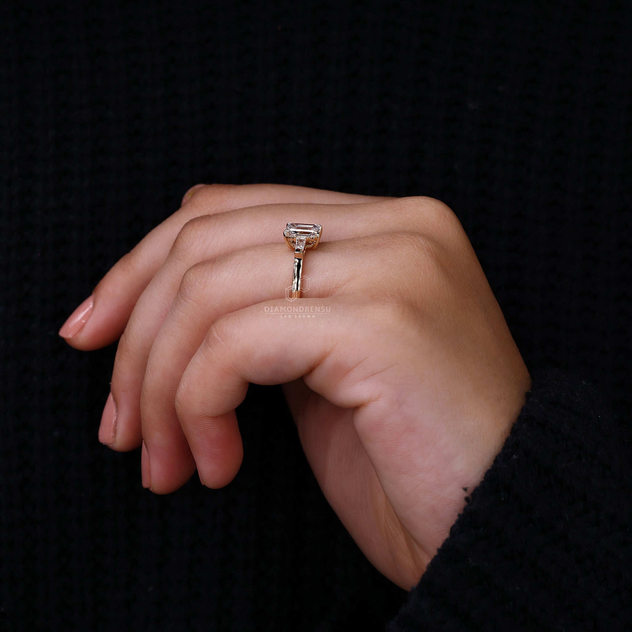 Proposal engagement ring with emerald cut centre and tapered side diamonds.
