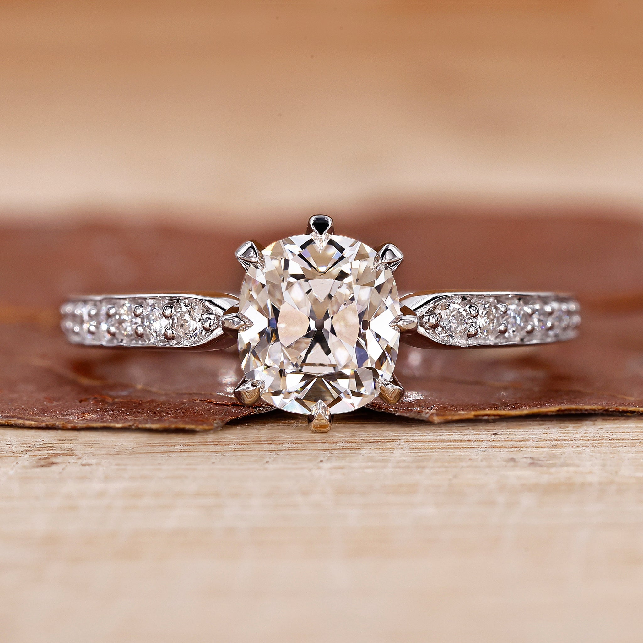 Old mine cushion cut diamond ring with pave set band in white gold.
