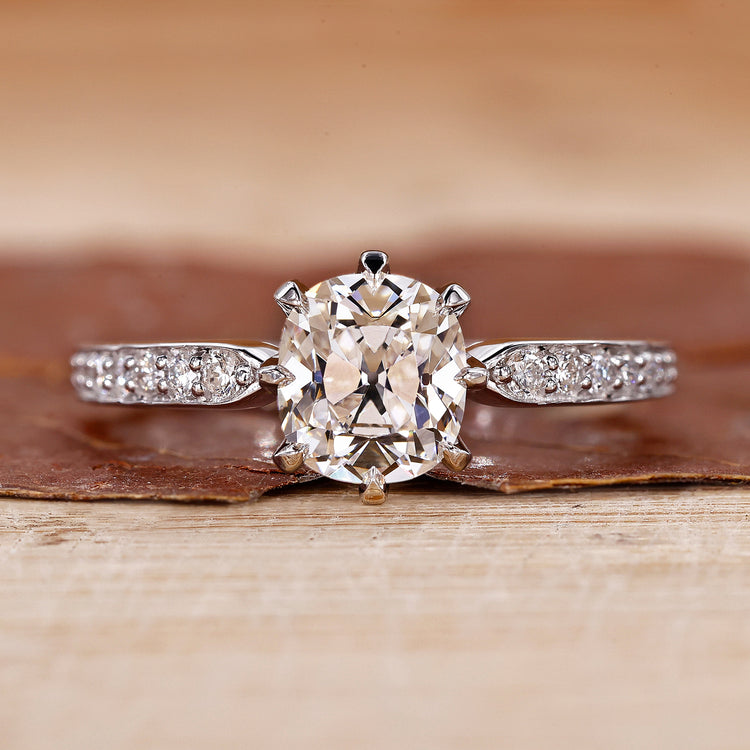 Old mine cushion cut diamond ring with pave set band in white gold.
