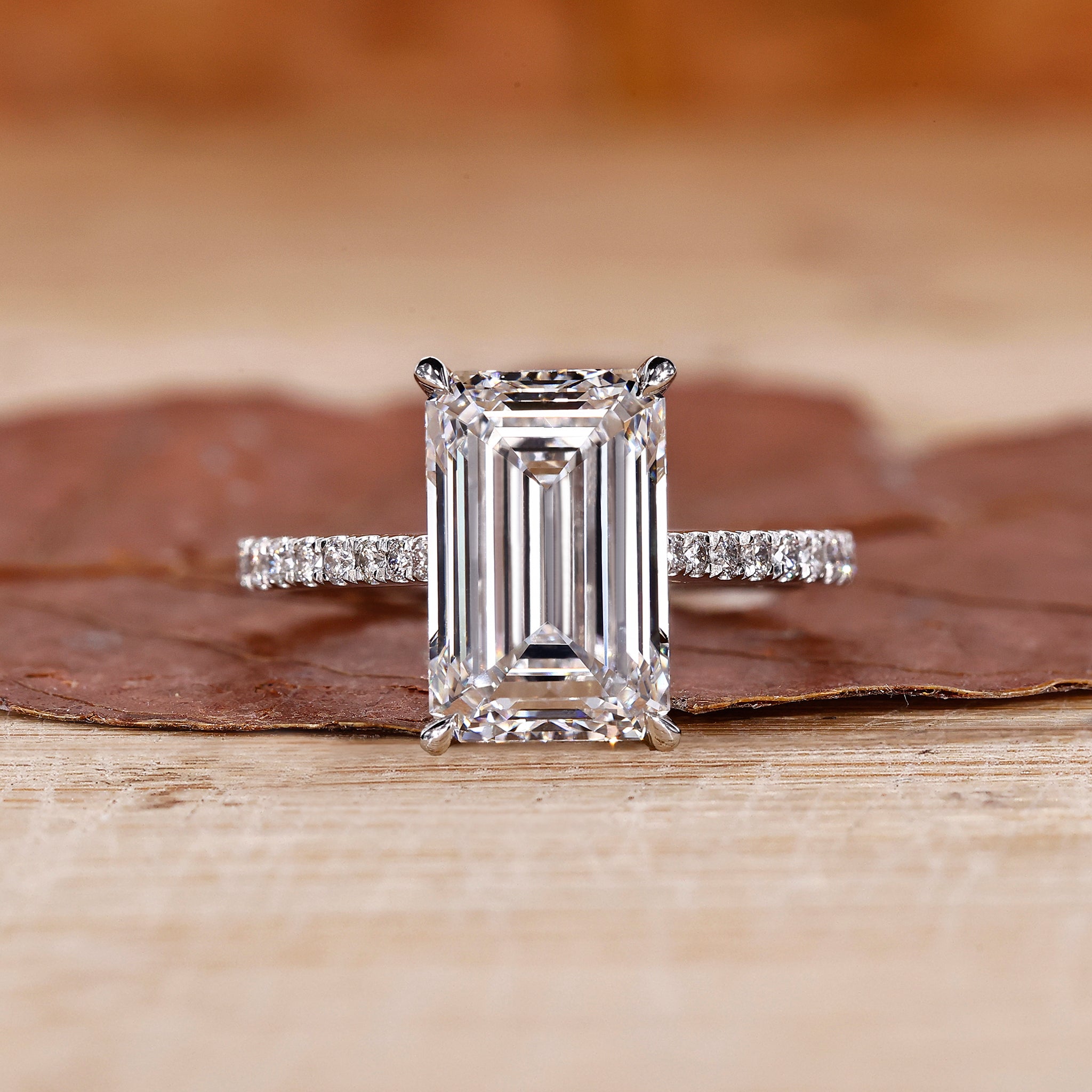 Emerald cut engagement ring with round stone pave accents.
