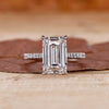 Emerald cut engagement ring with round stone pave accents.
