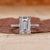 Emerald cut engagement ring with round stone pave accents.
