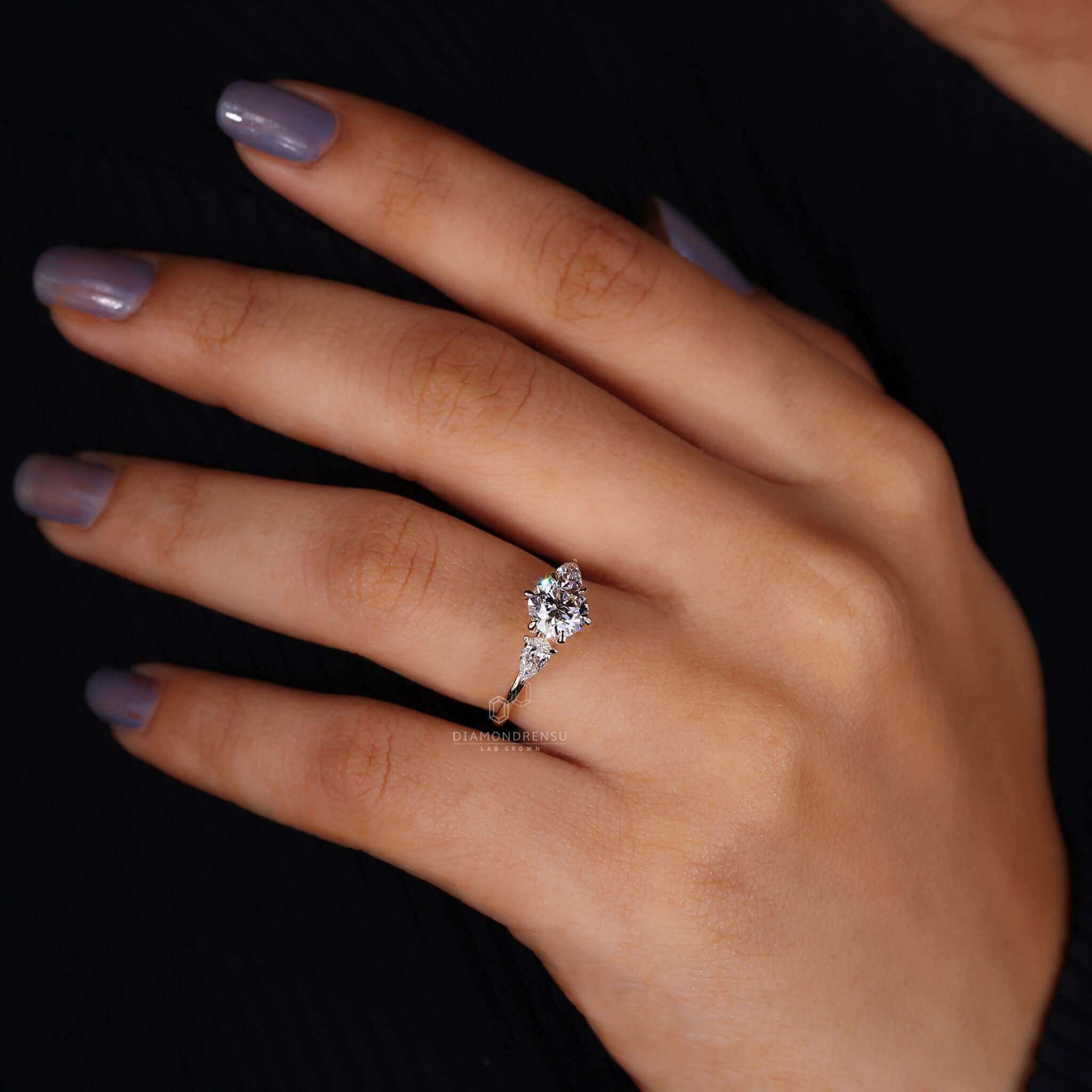 A beautiful round diamond engagement ring with pear side stones, designed for elegance.