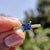 Princess cut moissanite ring with royal dark blue center stone in rose gold setting.
