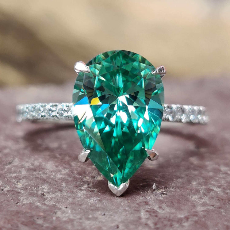 Pear cut moissanite ring with green center stone.

