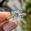 Princess cut moissanite ring with hidden halo and white gold band.