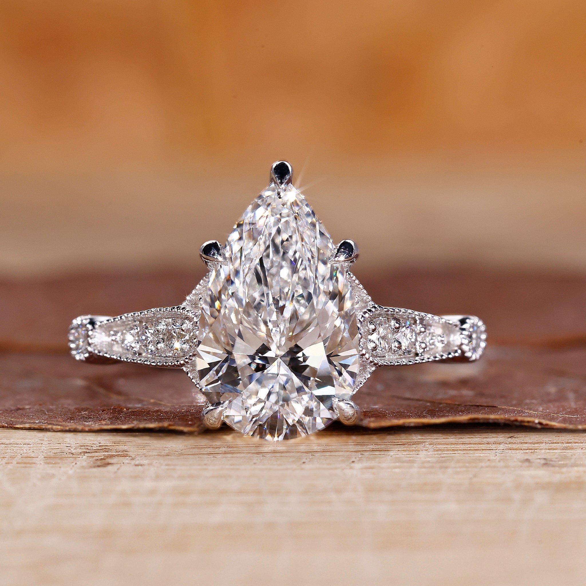 Pear diamond engagement ring with round side diamond in white gold.
