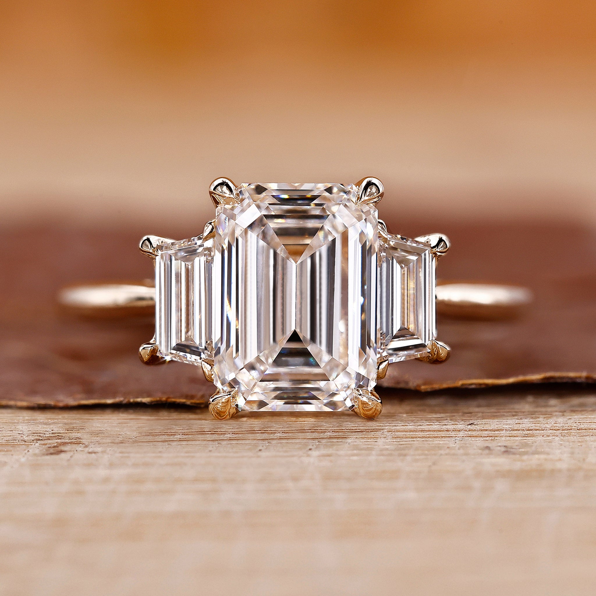 Three Stone Ring is made with emerald diamond and yellow gold.
