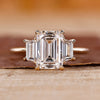 Three Stone Ring is made with emerald diamond and yellow gold.
